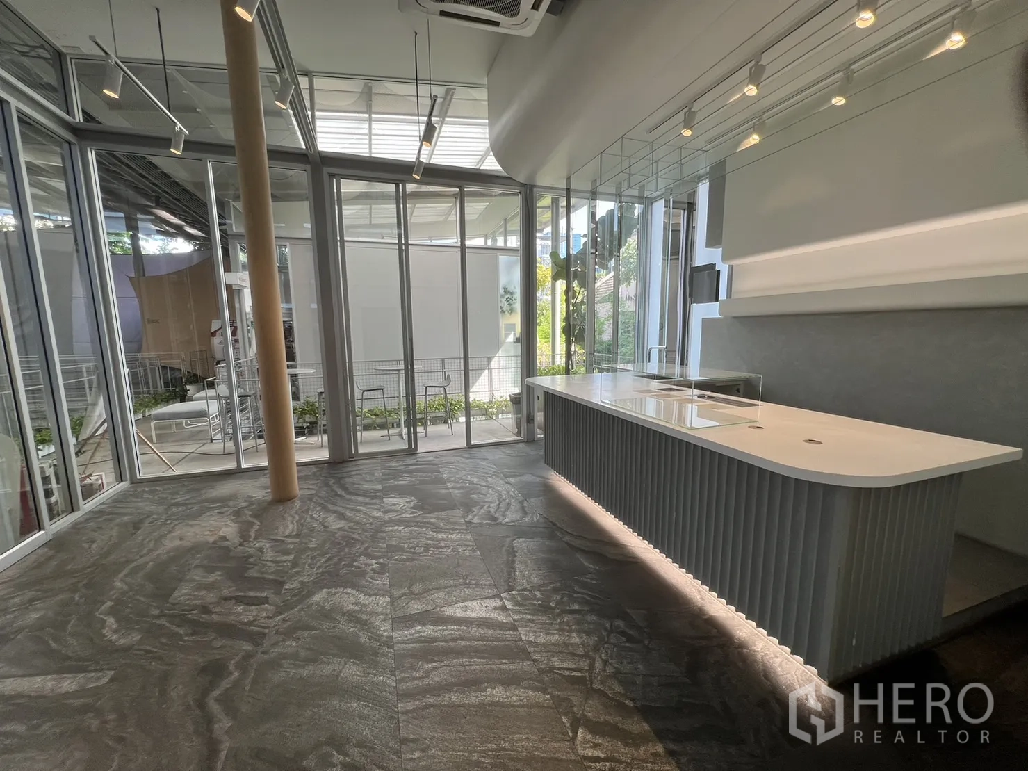 Retail Space for rent in Khlong Toei, Bangkok - Long illuminated display counter next to floor-to-ceiling windows with garden views in a modern retail unit.