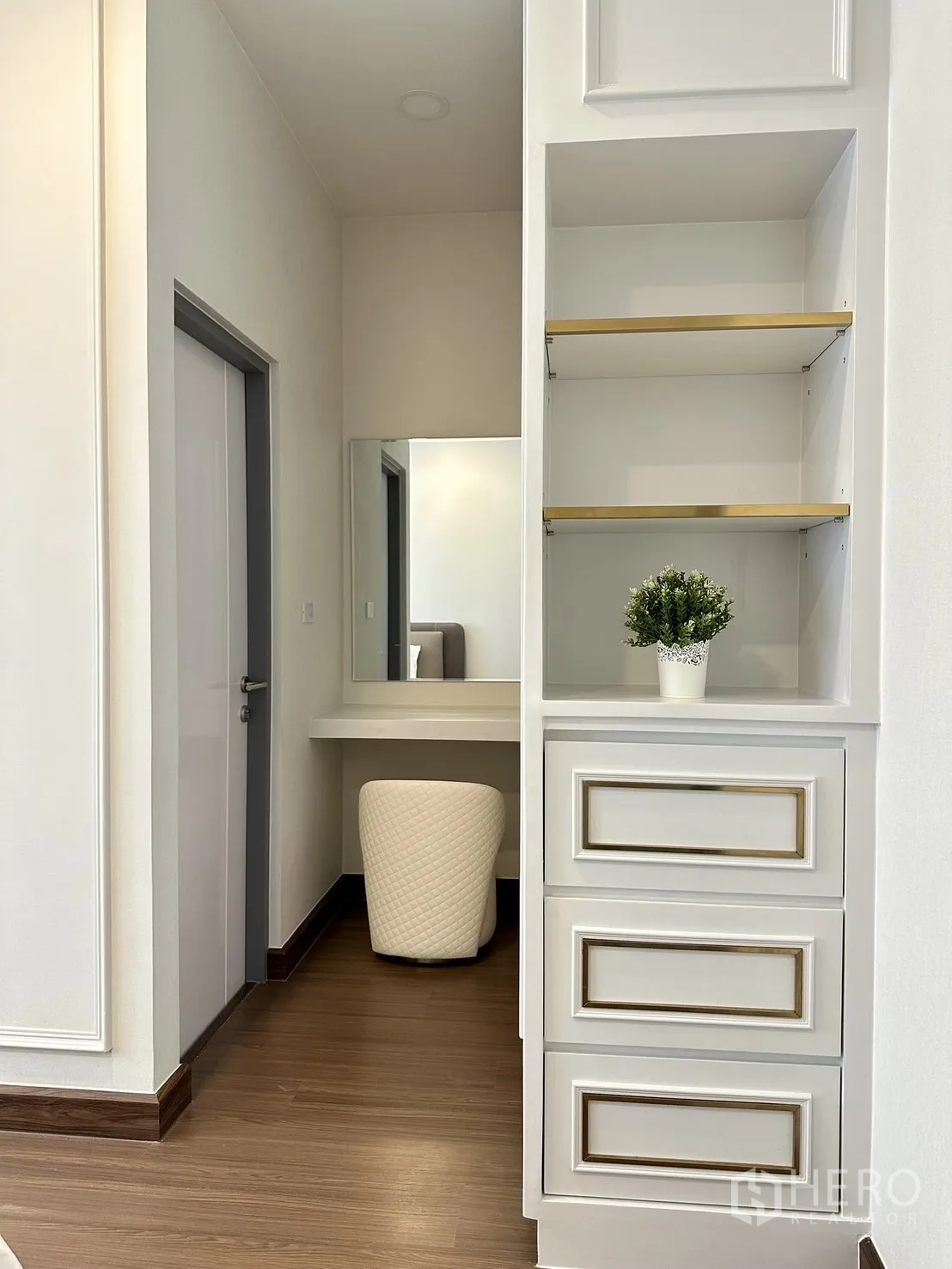 Detached House for rent or sale - Built-in shelving and vanity nook with mirror and quilted stool in white and gold tones.
