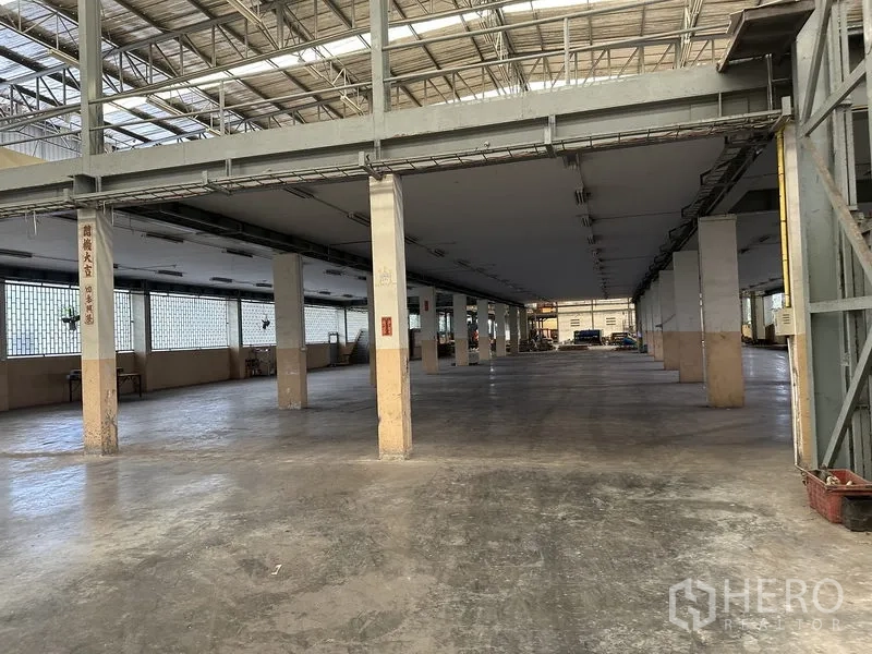 Factory for rent or sale in Lam Luk Ka, Pathum Thani - Large production floor under a mezzanine with concrete slab and square columns.