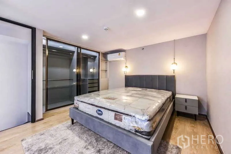 Condominium for rent in Huai Khwang, Bangkok - Spacious bedroom with new mattress, pendant lamps and wood flooring.