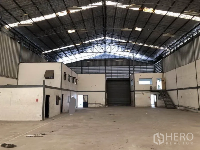 Warehouse for rent in Suan Luang, Bangkok - Open storage floor facing central loading bay with overhead lighting and office blocks.