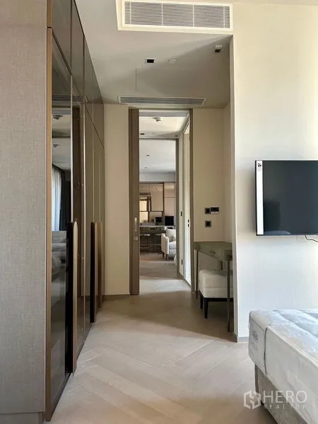 Condominium for rent - Bedroom corridor with mirrored wardrobes, wall-mounted TV and study nook.