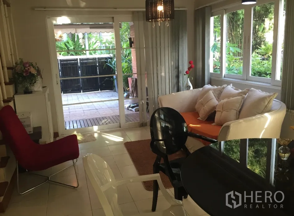 Townhouse for rent or sale in Bueng Kum, Bangkok - Ground-floor sitting and dining space with sliding doors to a small patio and greenery.