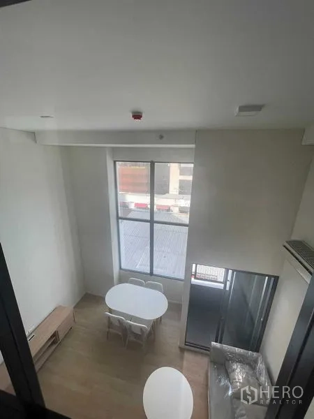 Condominium for rent in Khlong Toei, Bangkok - View from the mezzanine showing a dining set by a tall window in the open-plan space.