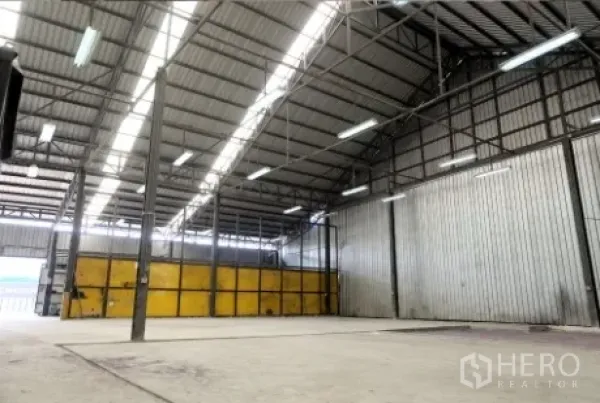 คลังสินค้า ให้เช่าในPak Kret, Nonthaburi - พื้นที่อุตสาหกรรมโล่ง ผนังเมทัลชีท มีสกายไลท์ และประตูบานเลื่อนสีเหลืองขนาดใหญ่