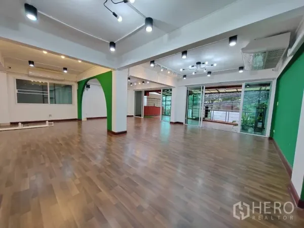 Retail Space for rent in Khlong Toei, Bangkok - Spacious sales floor with glass doors to terrace, ceiling spotlights and green arch