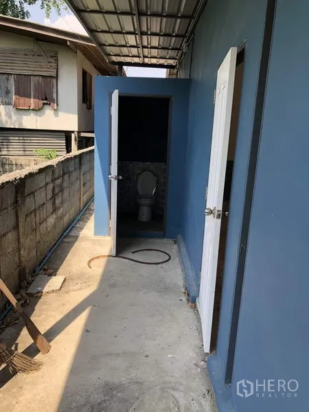 货栈 出售在Pathum Thani - 室外卫生间区域，蓝色墙面与金属雨棚，分设两扇白色门。