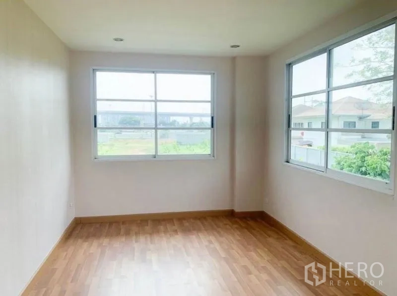 Detached House for sale in Saphan Sung, Bangkok - Corner bedroom with two large windows, laminate wood floor and estate views.