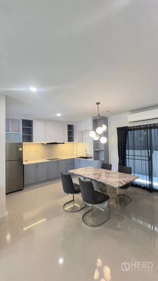 Townhouse for rent in Bang Phli, Samut Prakan - Open-plan dining and kitchen with marble table, pendant light and sliding door.