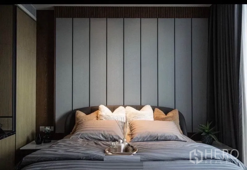 Condominium for rent in Khlong Toei, Bangkok - Bedroom with padded headboard, neutral bedding and accent pillows.
