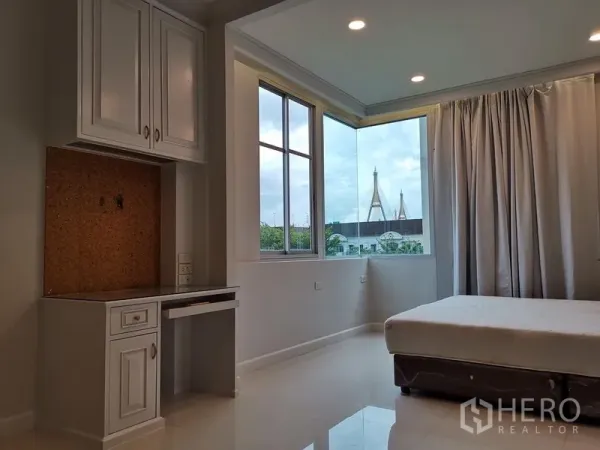 Townhouse for rent in Yan Nawa, Bangkok - Bedroom with built-in desk and cabinets, large corner windows showcasing Bhumibol Bridge.