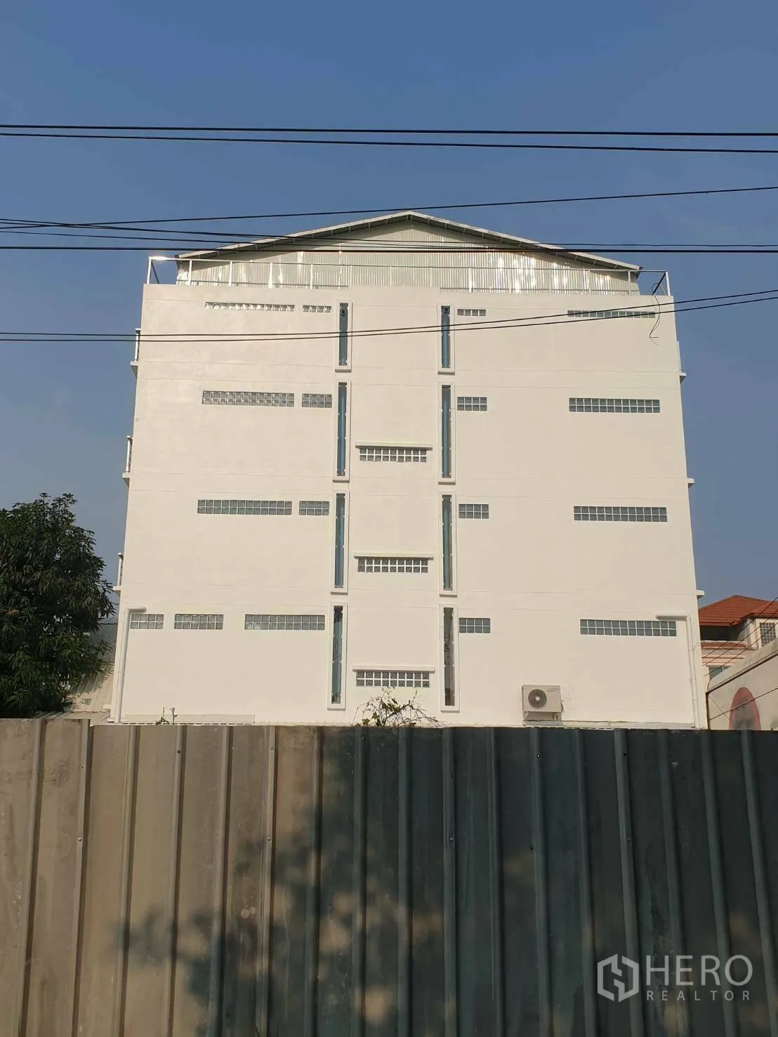 办公空间 出租或出售 - 高耸的白色商业建筑背立面，前方为金属围栏。