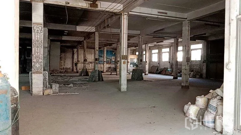 Warehouse for rent in Nakhon Pathom - Ground-floor production space with columns, windows and stacked materials on a concrete floor.
