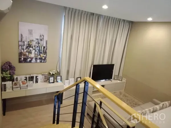 Townhouse for rent or sale in Suan Luang, Bangkok - Second-floor family lounge with sofa, TV console, artwork and draped windows beside the stairway.