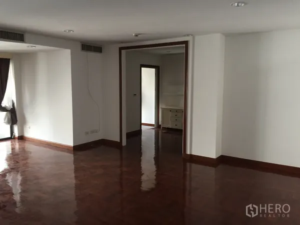 公寓 出租在Pathum Wan, Bangkok - 宽敞客厅，亮面人字拼木地板，通向相邻房间的大开口。