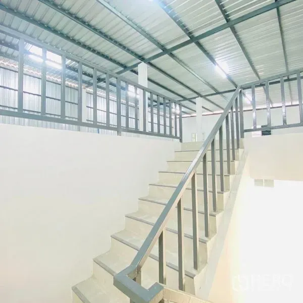 Warehouse for rent in Bang Khae, Bangkok - Internal staircase with metal handrail leading to a mezzanine or office level inside the warehouse.