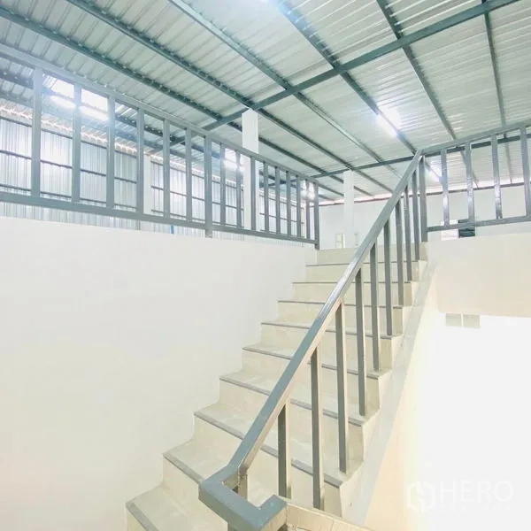 Warehouse for rent in Bang Khae, Bangkok - Internal staircase with metal handrail leading to a mezzanine or office level inside the warehouse.
