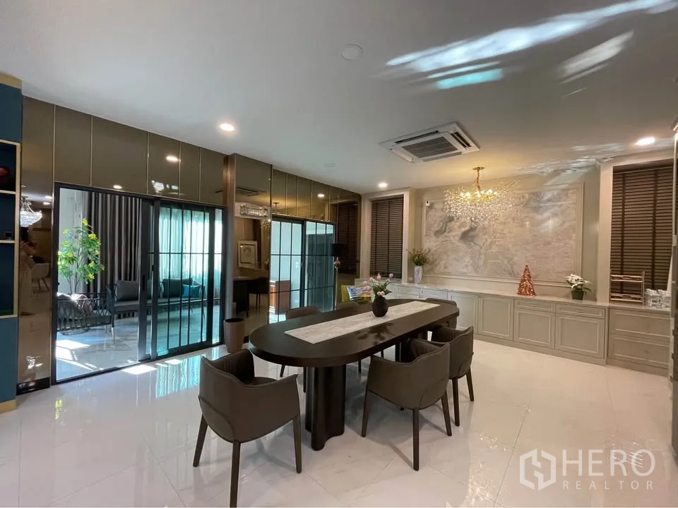 Detached House for rent or sale in Bang Phli, Samut Prakan - Open dining space with long table, sliding glass doors, and display cabinets.