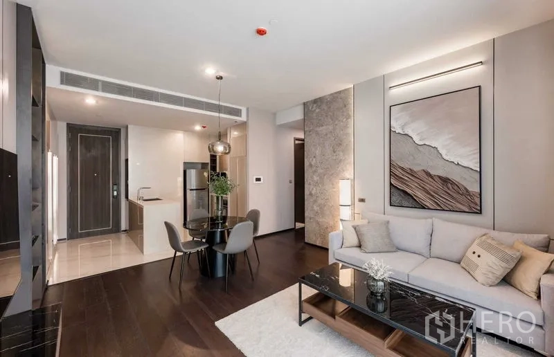 Condominium for rent in Watthana, Bangkok - Bright living room with sofa, round dining table and view toward the compact kitchen entry.