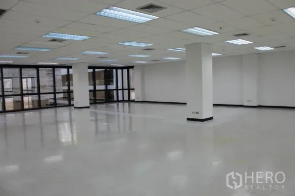 办公空间 出租在Watthana, Bangkok - 开放工位区，结构柱、吊顶和四周玻璃窗。