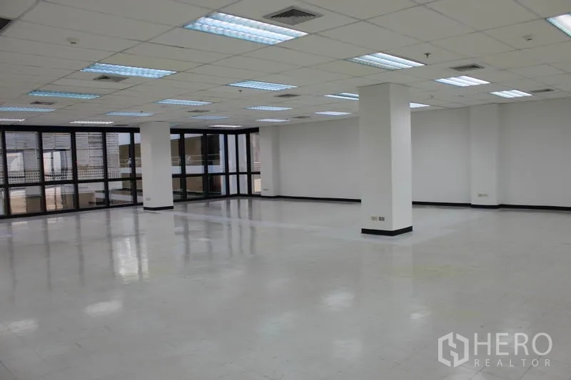 办公空间 出租在Watthana, Bangkok - 开放工位区，结构柱、吊顶和四周玻璃窗。