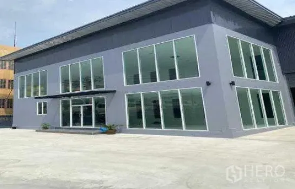 Warehouse for rent in Prawet, Bangkok - Modern two-storey glass-front office attached to the warehouse with a wide concrete forecourt.