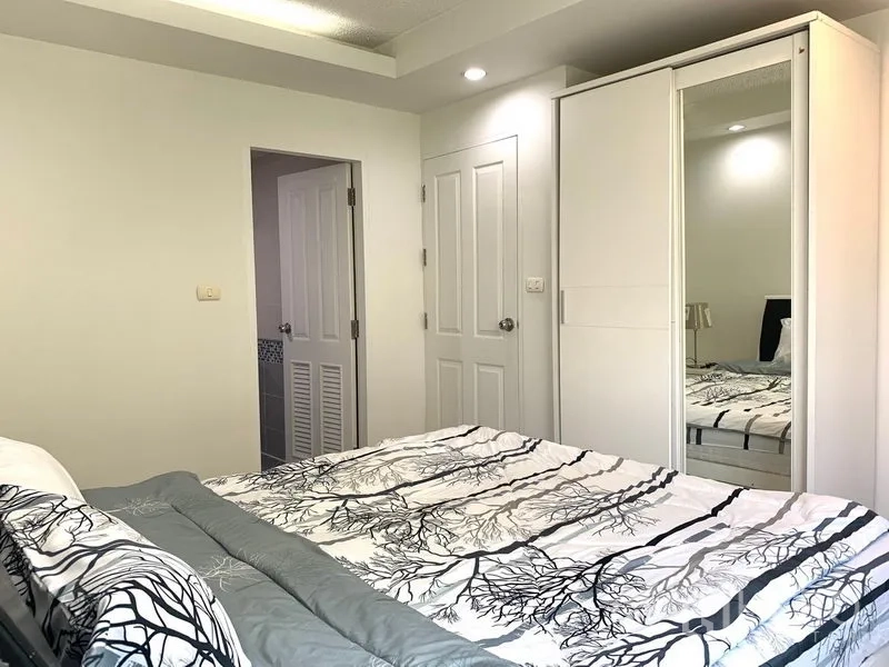 Condominium for rent or sale in Khlong Toei, Bangkok - Bedroom featuring sliding mirrored wardrobe, soft ceiling lights and a door to the bathroom.
