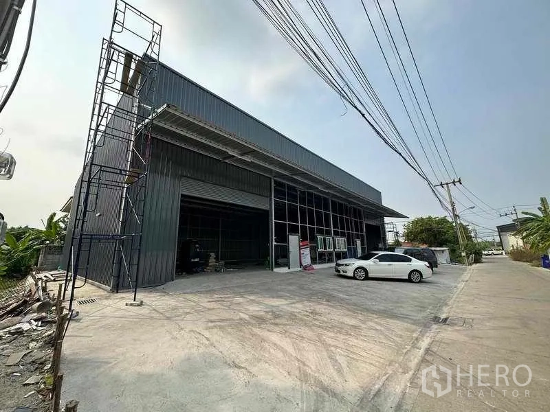 货栈 出租在Pak Kret, Nonthaburi - 仓库外立面斜角视图，装卸区、高挑雨棚与宽阔车道，便于货车出入。