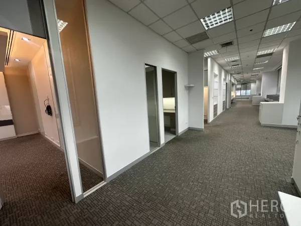 Office Space for rent in Watthana, Bangkok - Long office hallway leading to multiple rooms and a glass partition, carpet flooring.