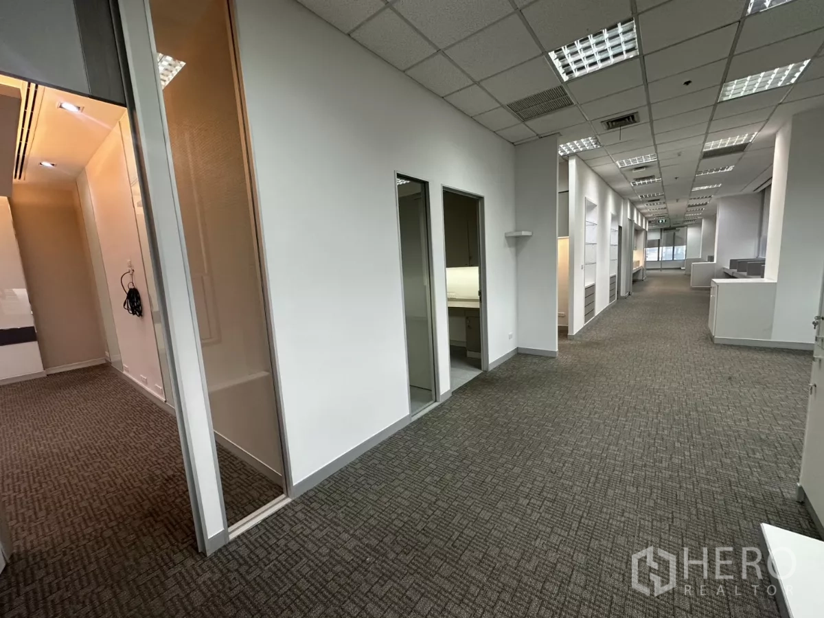 Office Space for rent in Watthana, Bangkok - Long office hallway leading to multiple rooms and a glass partition, carpet flooring.