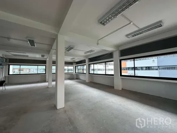 办公空间 出租在Watthana, Bangkok - 转角办公区配全景窗与外露灯具，布局灵活。