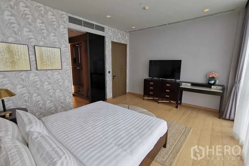 Condominium for rent or sale in Watthana, Bangkok - Bedroom with TV, desk and dresser beside the bed.