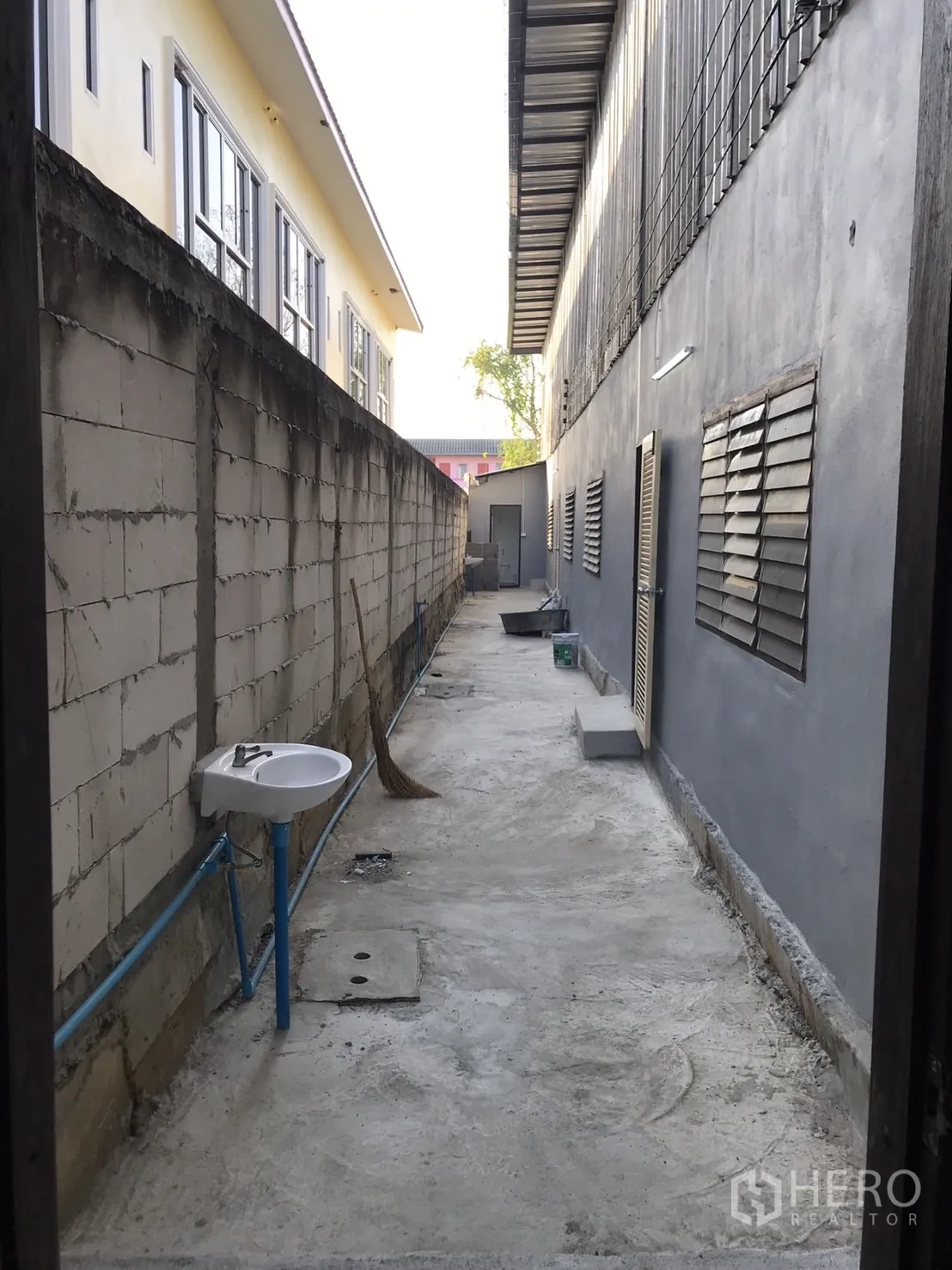 Warehouse for rent in Lam Luk Ka, Pathum Thani - Narrow side walkway behind the warehouse with ventilation windows and outdoor sink.