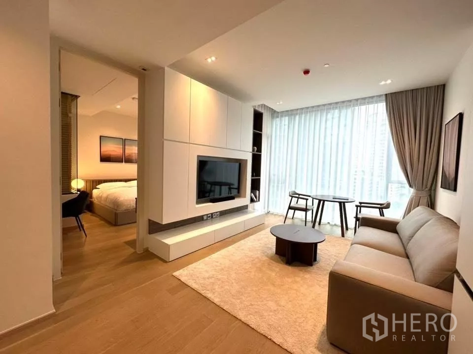 Condominium for rent in Bangkok - Modern living area with built-in media wall, round dining table by large windows, and open-plan layout.