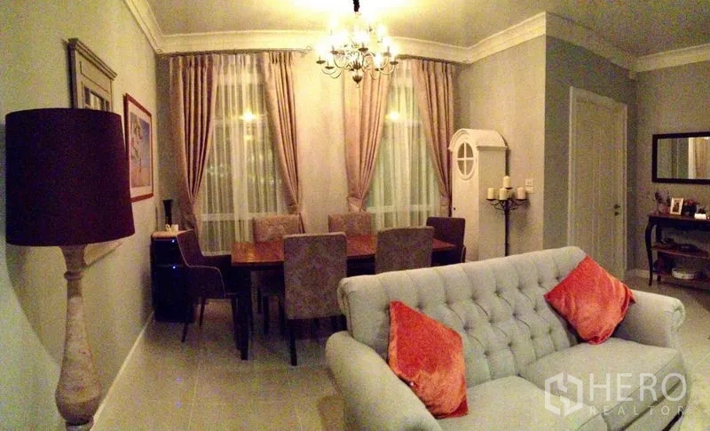 Townhouse for rent or sale in Bangkok - Elegant dining area with chandelier, six-seat table and sofa in an open-plan living space.