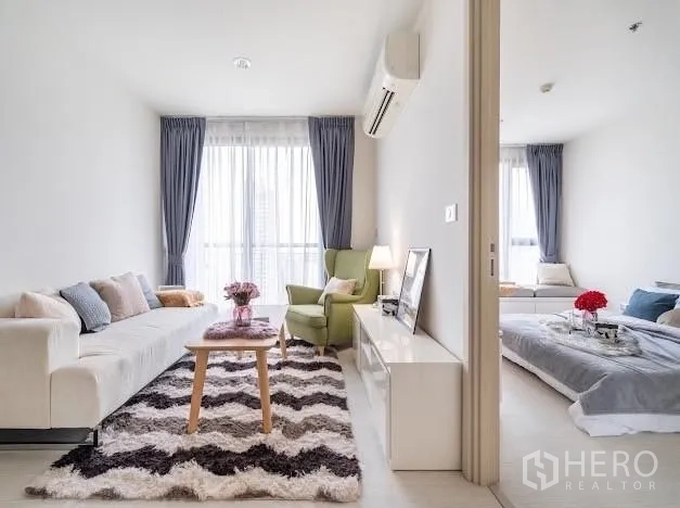 Condominium for sale in Khlong Toei, Bangkok - Living room connected to the bedroom via sliding door, both with large windows.