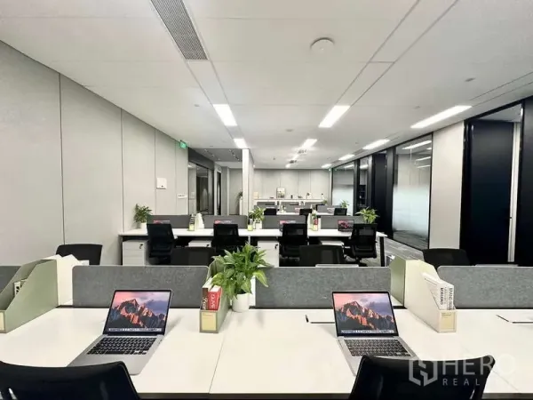 Office Space for rent in Bang Kapi, Bangkok - Modern open‑plan office with rows of workstations, grey partitions, laptops and potted plants under LED lighting.