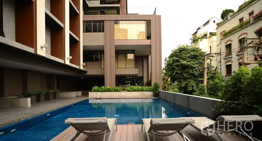 Condominium for rent or sale in Sathon, Bangkok - Modern condominium courtyard with outdoor swimming pool, sun loungers, and landscaped greenery in Sathon, Bangkok.
