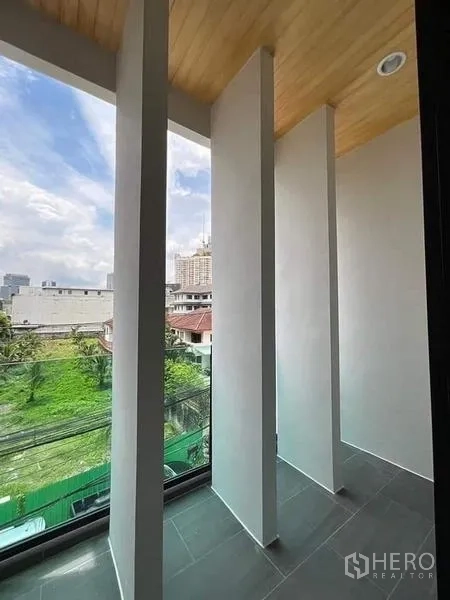 ทาวน์เฮาส์ ขายในWatthana, Bangkok - ระเบียงแคบมีซี่ตั้งและราวกระจก มองเห็นพื้นที่สีเขียวรอบบ้าน