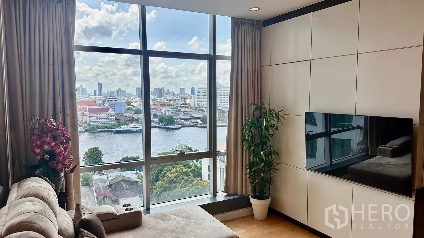Condominium for rent in Khlong San, Bangkok - Close-up of floor-to-ceiling window revealing the Chaophraya River and skyline view from the living room.
