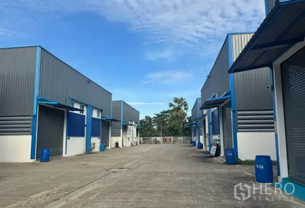 Warehouse for rent in Lam Luk Ka, Pathum Thani - Exterior view of a warehouse compound with multiple units and a wide driveway.