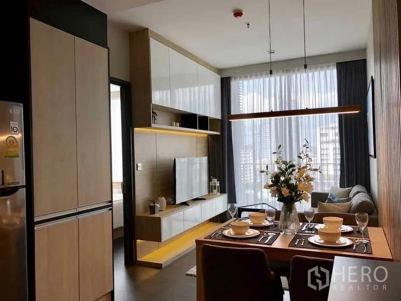 公寓 出租在Watthana, Bangkok - 开放式客餐厅，内置电视柜，落地窗外是城市天际线景观。