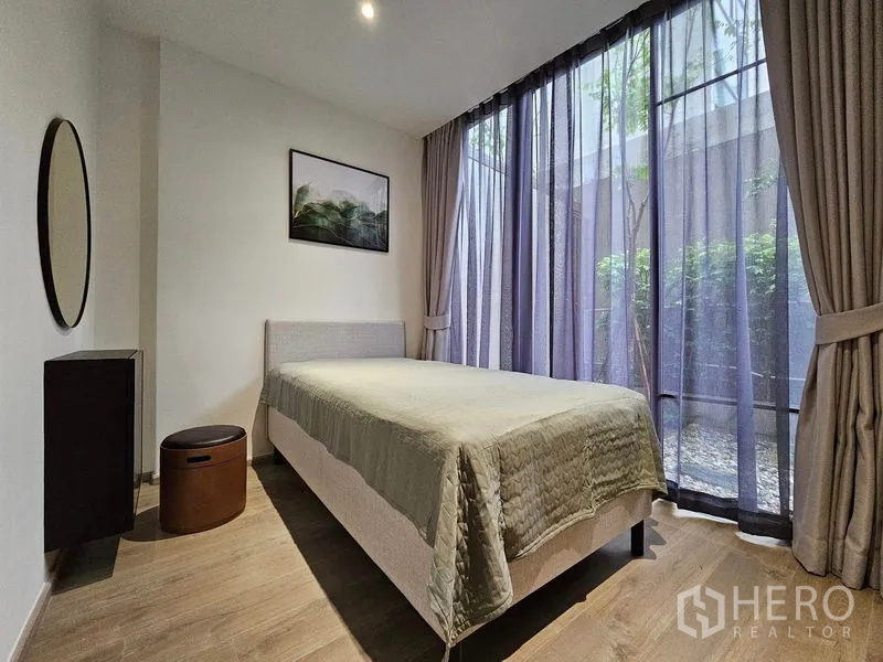 Condominium for rent or sale - Guest bedroom with single bed and sheer curtains opening to a landscaped courtyard.