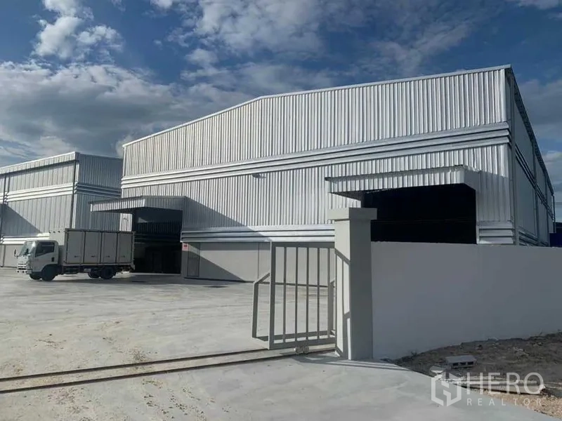 货栈 出租在Ban Bueng, Chon Buri - 前门与仓库立面，可见送货卡车与装卸入口。