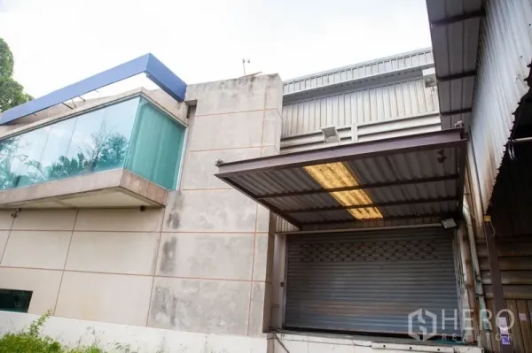 Warehouse for rent in Prawet, Bangkok - Warehouse loading bay with roller shutter door, canopy roof and a cantilevered glass corner office.
