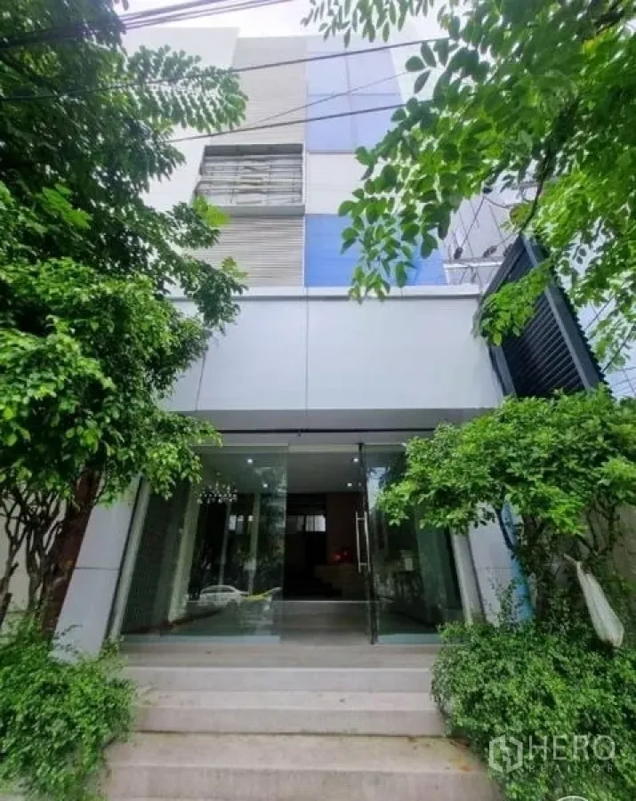 店屋 出租在Watthana, Bangkok - 现代立面再现，绿植映衬的玻璃门入口。