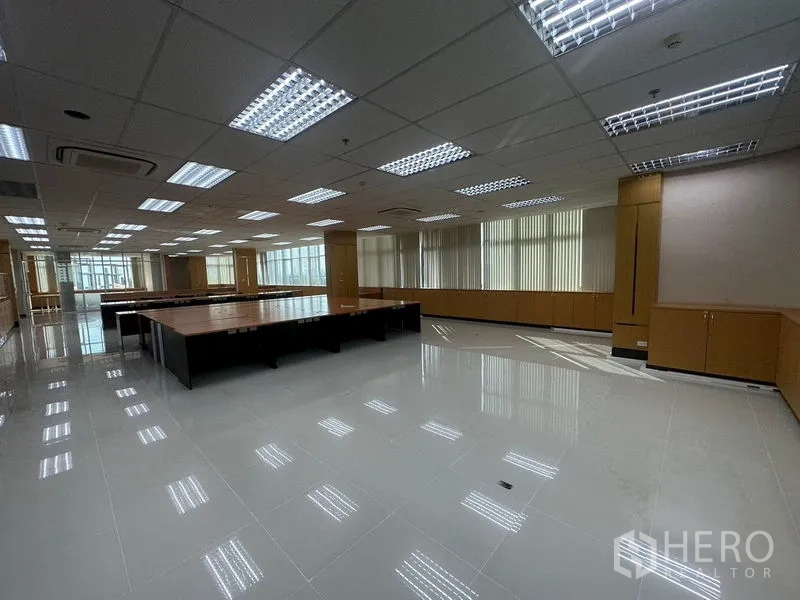 Office Space for rent in Suan Luang, Bangkok - Large open area with polished tiles, long built-in cabinets beneath windows, and strip lighting.
