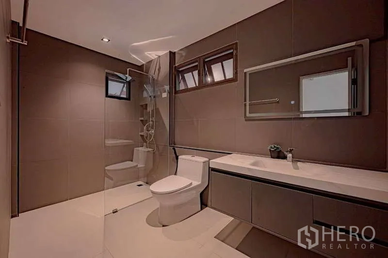 Detached House for rent or sale in Phra Khanong, Bangkok - Stylish bathroom with glass-partition shower, wall mirror, and modern fittings.