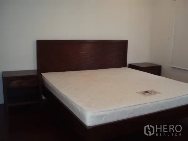 公寓 出租在Ratchathewi, Bangkok - 宽敞卧室，木质床架、床垫与双床头柜，拉差贴威公寓。