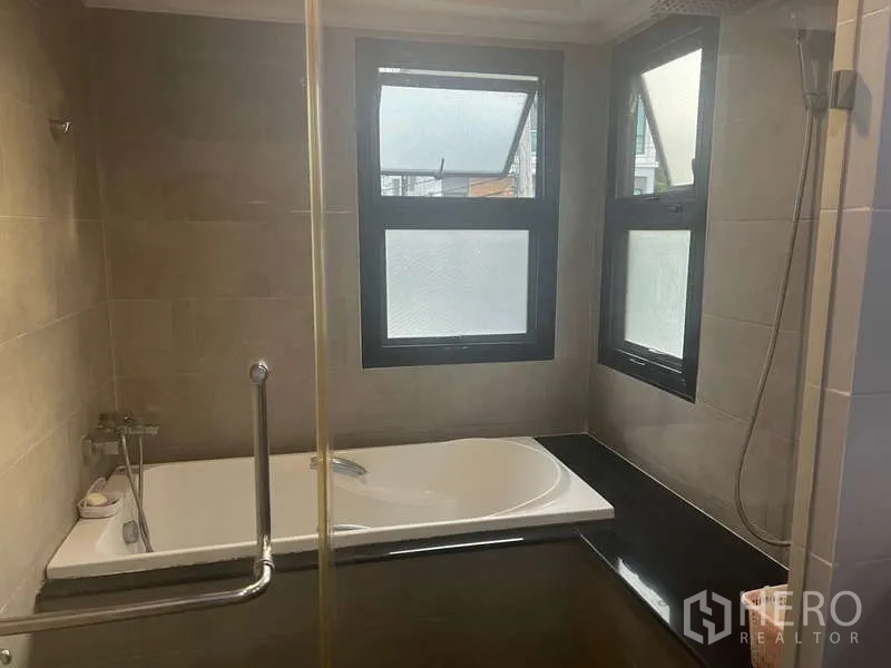 Detached House for rent or sale in Prawet, Bangkok - Bathroom with bathtub, glass shower partition and frosted windows.